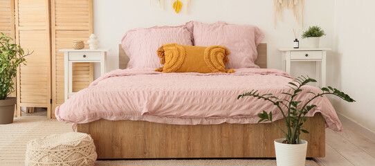 Bed with stylish pink bedding in interior of bedroom