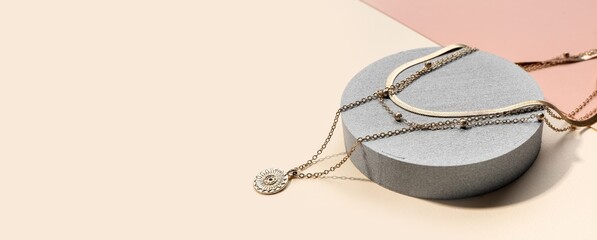 Decorative podium and beautiful necklaces on color background with space for text