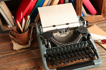 Vintage typewriter on wooden table near shelves with books