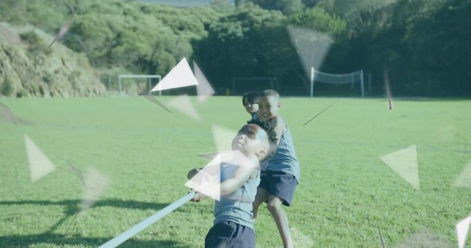 Three boys tugging rope in sports tug-of-war on field with drifting triangles then celebrating