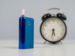 Electronic cigarette and alarm clock on white background. Tobacco heating systems.