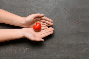 Female hands with red heart on black background
