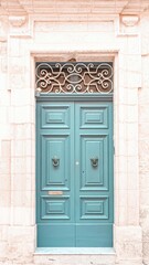 Teal Door in Historic Building with Ornate Ironwork and Stone Frame Facade