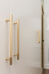 Modern elegance captured: polished chrome door handle with sharp linear geometry contrasting smooth white lacquered panel