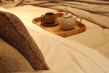 Bandeja de café da manhã com bule e xícaras sobre cama confortável, em cenário acolhedor e relaxante / Breakfast tray with teapot and cups on comfortable cozy bed