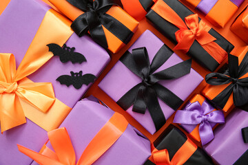 Halloween gifts and bats on orange background. Top view