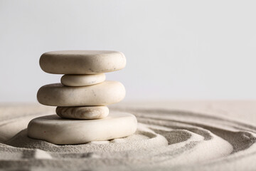 Stack of stones on sand with lines against light background. Zen concept