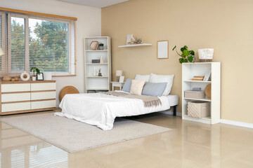 Modern interior on bedroom with comfortable bed, chest of drawers and shelving units