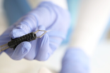 Veterinarian holding tick extractor with parasite and cat's fur in vet clinic, closeup