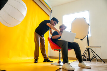 Photographer And Model Share A laugh While Reviewing Photos On A Laptop During A Fun Studio Session