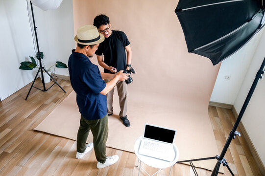 Photographer And Model Review Photos On Camera Screen During Studio Shoot