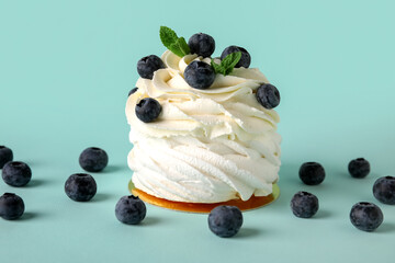 Sweet Pavlova cake with fresh blueberries and mint on blue background