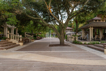 Peaceful outdoor pathway lined with trees and gazebos in a serene park setting at dusk on Hilton...