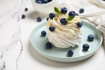 Plate of sweet Pavlova cake with fresh blueberries and mint on white background, closeup