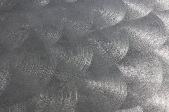Metallic surface with circular swirl patterns close-up abstract textured background