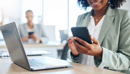 Business professional using a phone to text or email in an office, networking via a social media app. Close-up of hands with a laptop nearby as a secretary types on the mobile device for research.	
