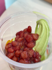 Matcha tea ice cream served with red bean topping close up background. Stock photo.