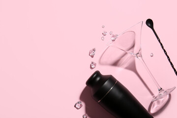 Shaker, mixing spoon, glass and ice cubes on pink background
