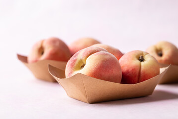 Fresh peaches in paper bowl on pink background, Summer fruit