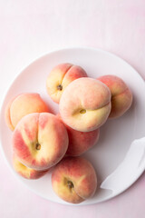 Top view of fresh peaches on white plate with pink background, Summer fruit