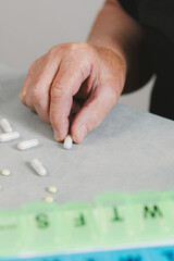 A woman's hand preparing to place a capsule pill into a plastic container.