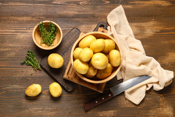 Bowl with raw baby potatoes and thyme on wooden background