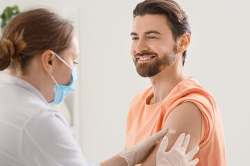 Young man with doctor applying medical patch after vaccination in clinic