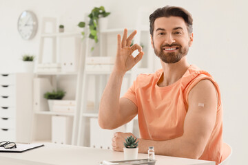 Young man with applied medical patch showing OK after vaccination in clinic