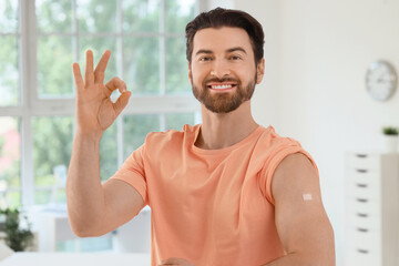 Young man with applied medical patch showing OK after vaccination in clinic