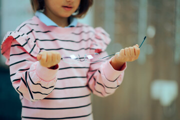 Little Girl Bending Titanium Alloy Glasses Frame. Child in an optical store almost breaking new...