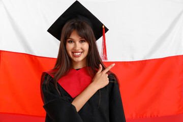 Female graduate pointing at something against flag of Poland