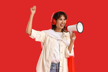 Young woman in headphones with flag of Poland shouting into megaphone on red background