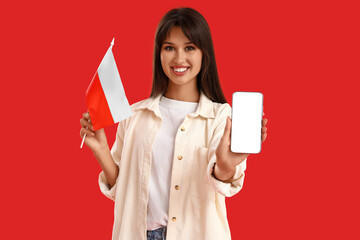 Young woman with flag of Poland and blank mobile phone on red background