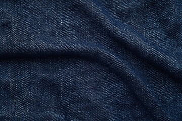 close-up of dark blue denim fabric showing detailed texture and weave pattern with subtle folds and shadows