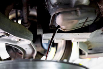 Car mechanic drain the old lubricant engine oil