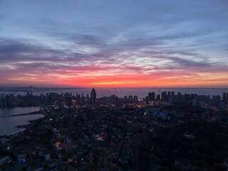 Obraz premium Artistic young woman enjoys the beautiful evening glow over Qingdao, China while the city lights begin to shine
