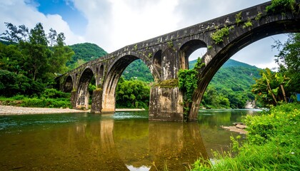 Fototapeta premium Stone arch bridge over a river in a lush valley
