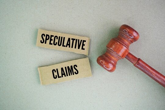Judge's hammer and paper with the word speculative claims. Possible financial loss or expenses claimed by a plaintiff that are contingent upon a future occurrence