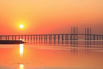 Stunning sunset over Jiaozhou Bay Bridge in Qingdao, China, highlighting serene coastal beauty and...