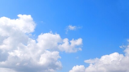 Fototapeta premium Clear blue sky with white clouds. Panoramic blue sky background with fluffy white cumulus clouds. Aerial view of cloudscape on sunny day.