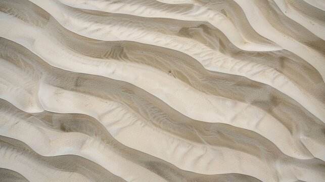 Windblown sand texture with smooth parallel ridges in light brown natural desert patterns showing erosion and geological formation details under sunlight.