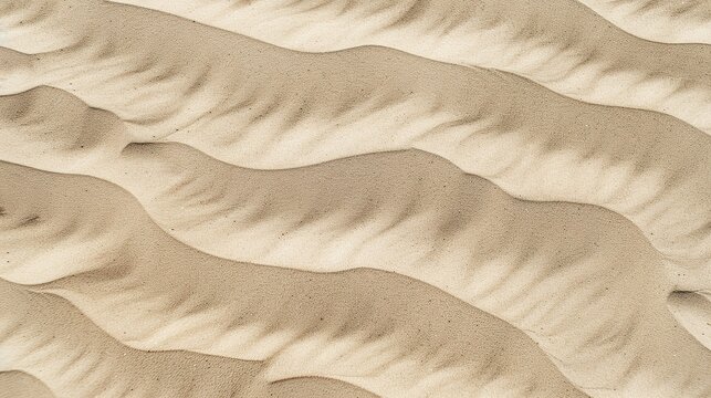 Windblown sand texture with smooth parallel ridges in light brown natural desert patterns showing erosion and geological formation details under sunlight.