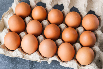 Fresh brown eggs nestled in a rustic, textured paper egg carton. The warm, earthy tones of the eggs highlight concepts of natural food, healthy ingredients, and sustainable packaging.