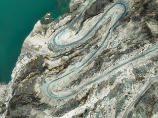 Industrial scene with truck in motion on winding quarry road, carrying extracted stone from open...
