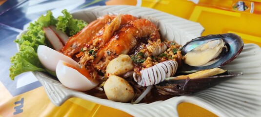 Tom Yum seafood noodles with thick broth, mussels, shrimp, squid, fish balls and soft-boiled eggs.