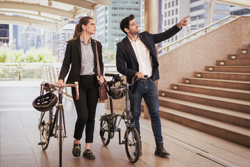 Commuting to work with bicycle. Businessman and businesswoman cycling to office in downtown...