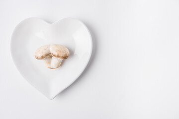 aw mushrooms laying on heart shaped plate on white background
