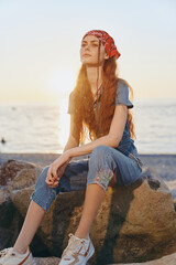 Lifestyle woman in modern boho-western denim street style with film color effect sitting on rocks...