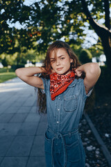 Lifestyle woman in modern boho-western denim street style wearing a red bandana, standing outdoors...
