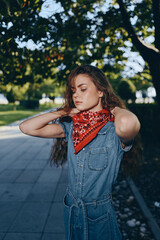Lifestyle woman in modern boho-western denim street style with a vibrant red bandana, captured with...